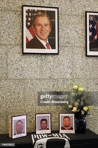 Photographs of three kidnapped Defense Department contractors, Thomas Howes, left, Keith Stansell, center, and Marc Gonsalves, sit on a table covered...