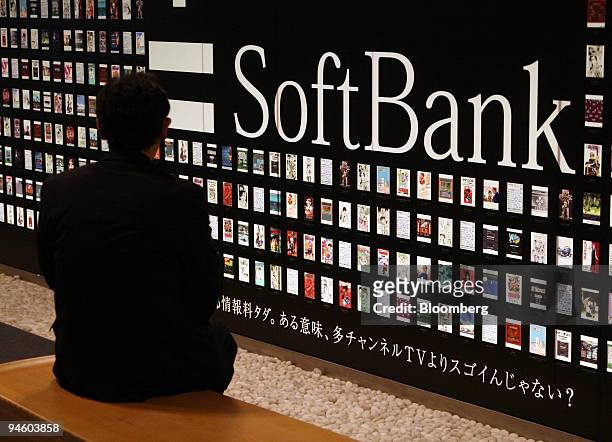 Man sits by a Softbank Corp. Sign in Tokyo, Japan, on Monday, May 7, 2007. Softbank Corp., Japan's third-biggest mobile-phone company, expects to...