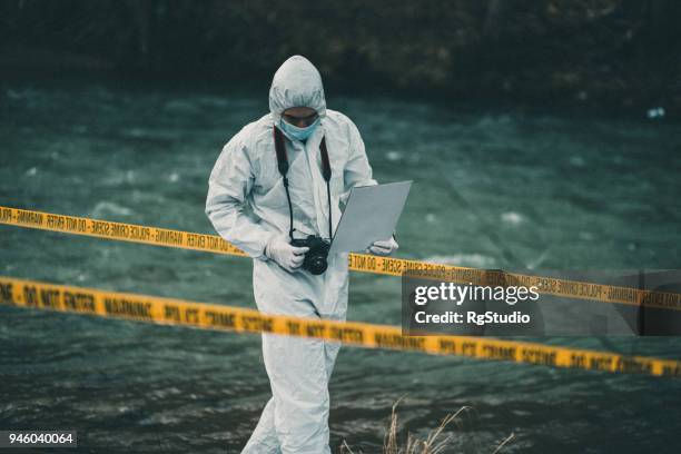 forensic pathologist holding a ca,era looking down searching for evidence - forensic stock pictures, royalty-free photos & images