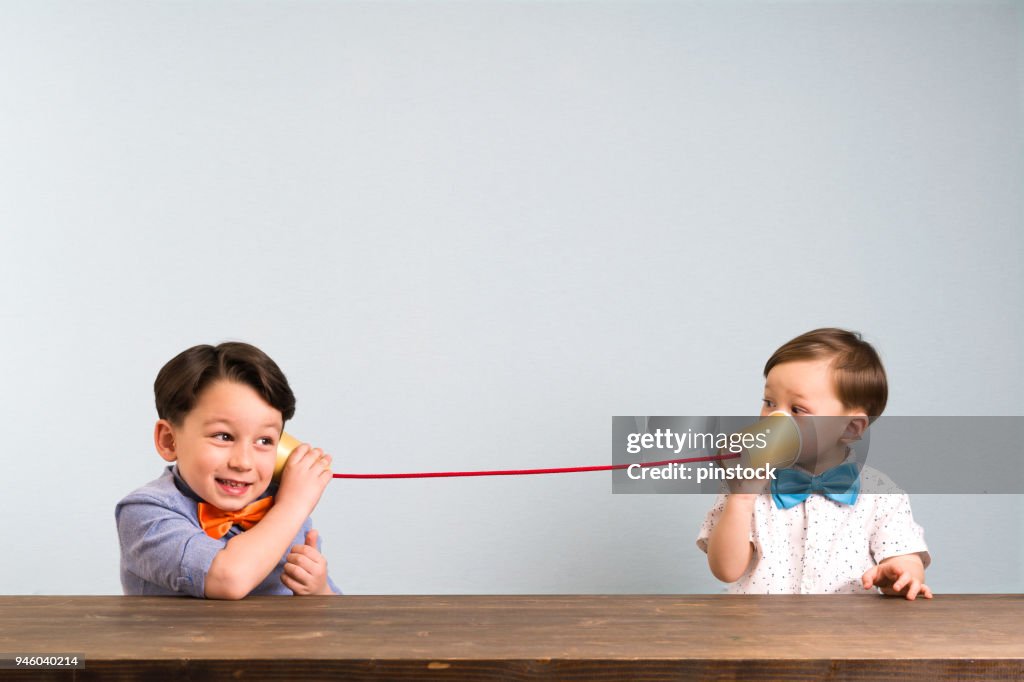 兩孩子們用紙杯作為電話