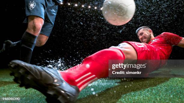 soccer player trying to slide tackle his opponent - man tackling stock pictures, royalty-free photos & images