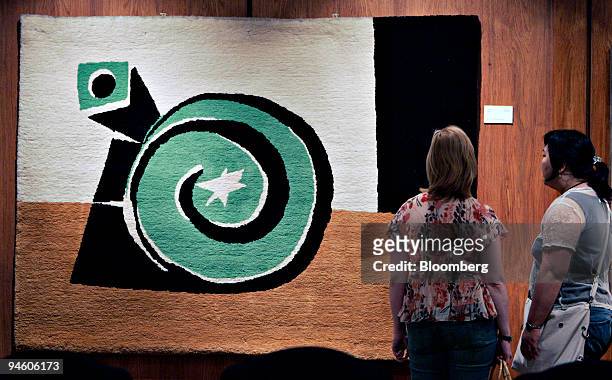 Two Kmart emplyees look over a tapestry by Pablo Picasso during a preview of items to be auctioned from the Kmart corporate art collection at their...