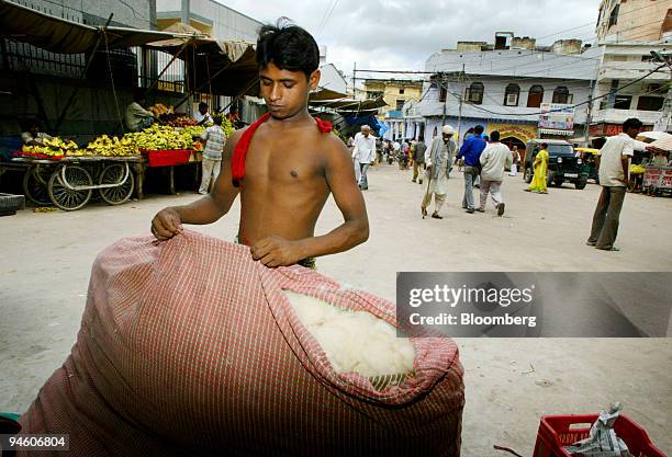 Man sews a mattress filled with cotton outside his shop in the Mehrauli Urban village of New Delhi, India, Tuesday, August 1, 2006. India, the...