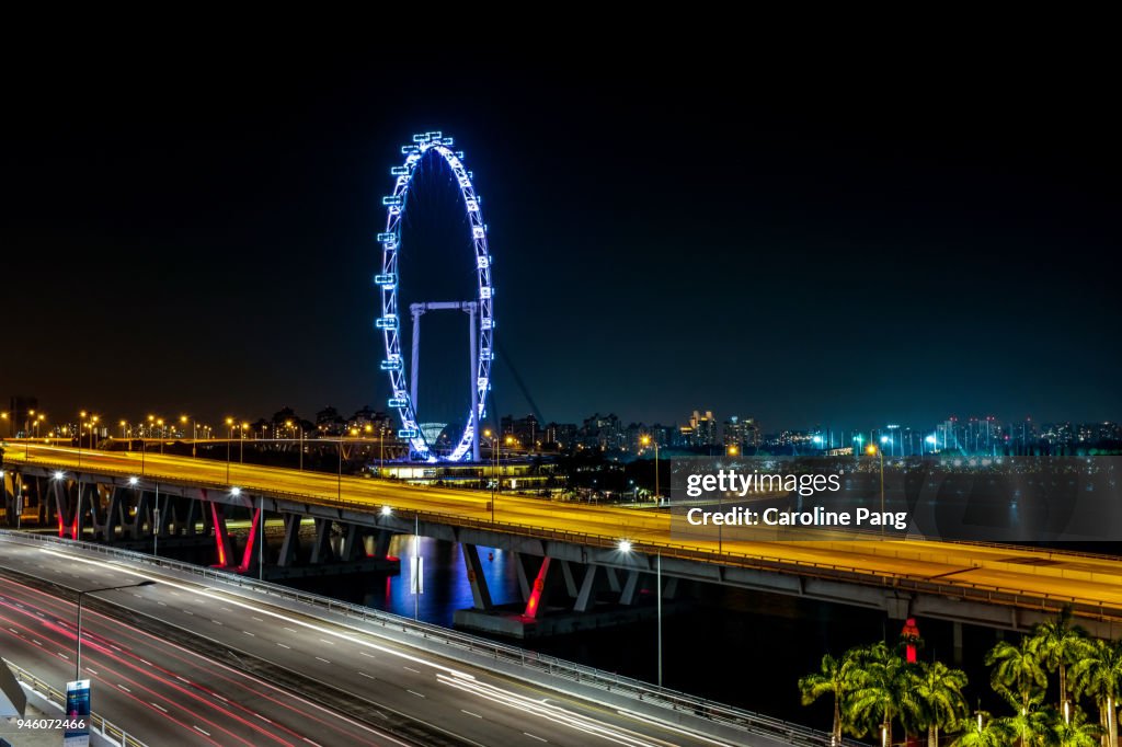 Vibrant and illuminating night scene of the Singapore Flyer and highway.