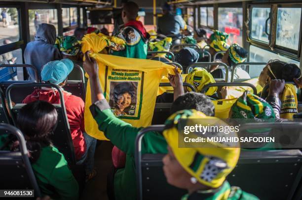 Woman holds a shirt with the picture of Winnie Madikizela-Mandela as people are on their way by bus to Orlando Stadium for Mandela's funeral ceremony...