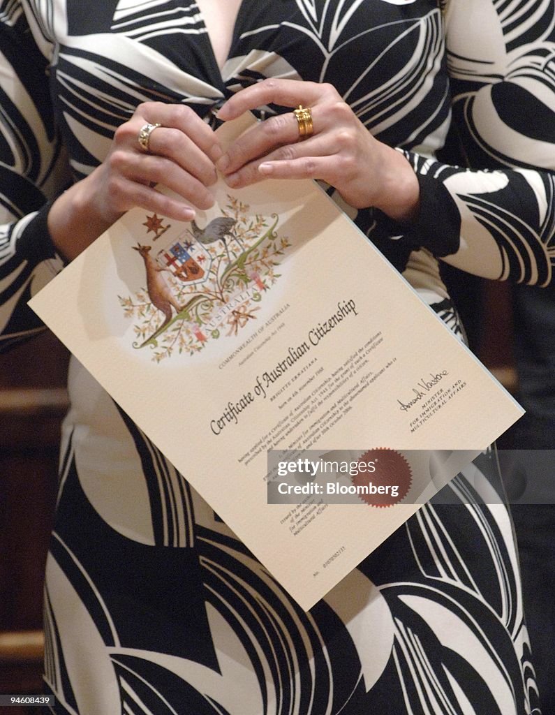 A woman holds her Citizenship Certificate after a ceremony a