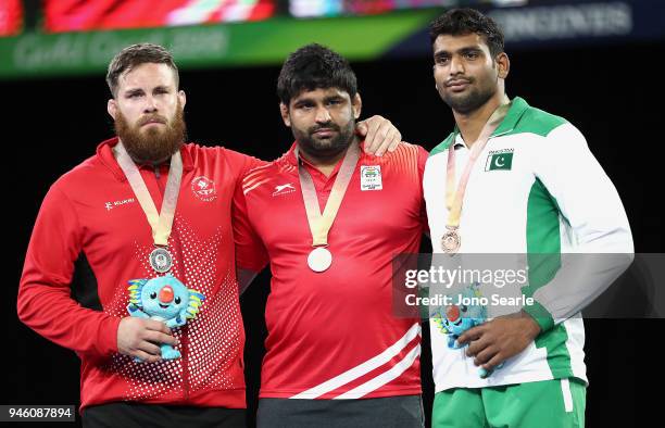 Silver Medalist Korey Jarvis of Canada, gold medalist Sumit of India and bronze medalist Tayab Raza of Pakistan pose during the medal ceremony for...