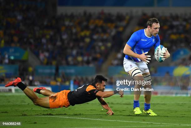 Scott Riddell of Scotland breaks the tackle of Muhamad Firdaus Tarmizi of Malaysia during the Rugby Sevens Men's Pool A match between Scotland and...