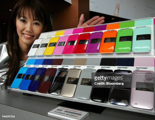 Shop employee poses with Softbank Corp. 812SH mobile phones on display in Tokyo, Japan, on Monday, May 7, 2007. Softbank Corp., Japan's third-biggest...