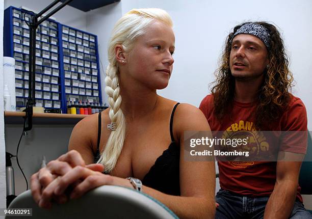 Jan Wirl, a tattoo artist, right, speaks to Tini Kloss, a student, after drawing a tattoo of the Chinese symbols for the five elements on her back in...