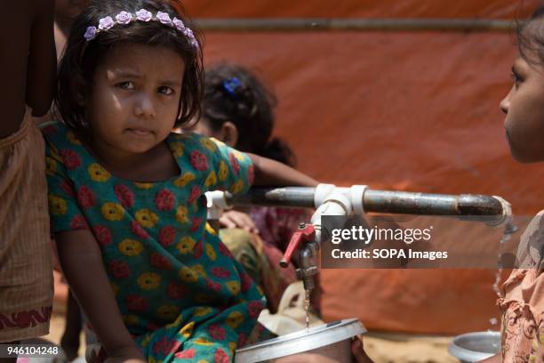 Young girl sits waiting for her containers to fill up at a water well in Kutupalong refugee camp. There are now approximately 600,000 Rohingya...