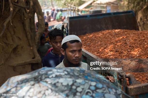 People walk through the busy streets of Kutupalong full of lorries with building materials for roads and steps needed during monsoon season. There...