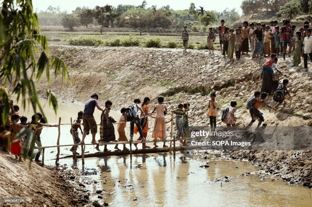 Children cross a makeshift bridge over a stream of sewage...