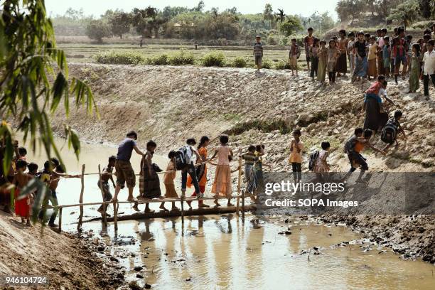 Children cross a makeshift bridge over a stream of sewage into nearby fields to play games. There are now approximately 600,000 Rohingya refugees in...