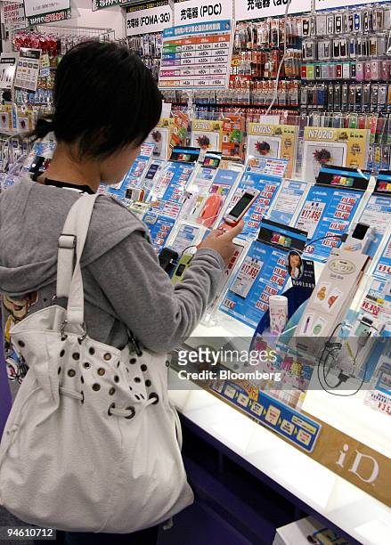 Woman looks at NTT DoCoMo Inc's mobile phones in a store in Tokyo, Japan, on Friday, October 27, 2006. Japan's consumer price gains unexpectedly...
