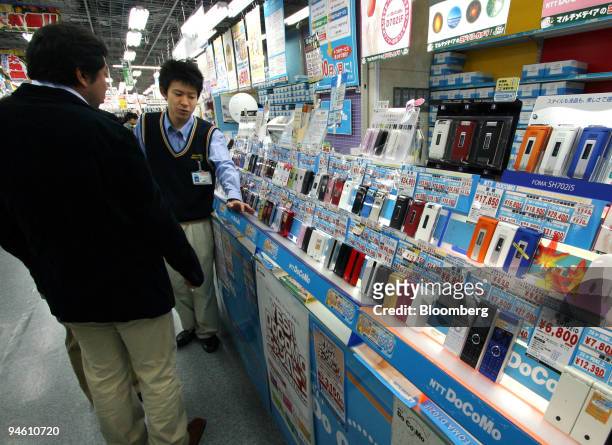 Man looks at NTT DoCoMo mobile phones in a store in Tokyo, Japan, on Friday, October 27, 2006. Japan's consumer price gains unexpectedly slowed,...