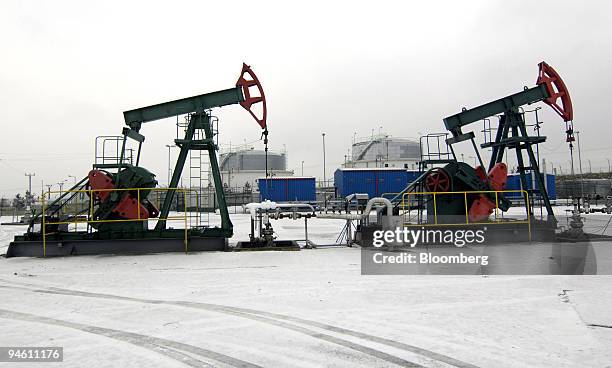 Nodding donkey oil pumps, operated by Moravske Naftove Doly a.s at work against a background of gas storage tanks in Uhrice, Czech Republic, on...