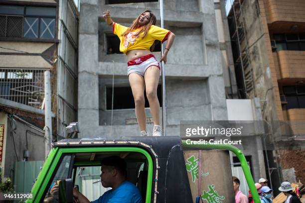Pole dancer performs on the roof of a car as it joins the procession following the sedan chair carrying a statue of the goddess Mazu as it is carried...