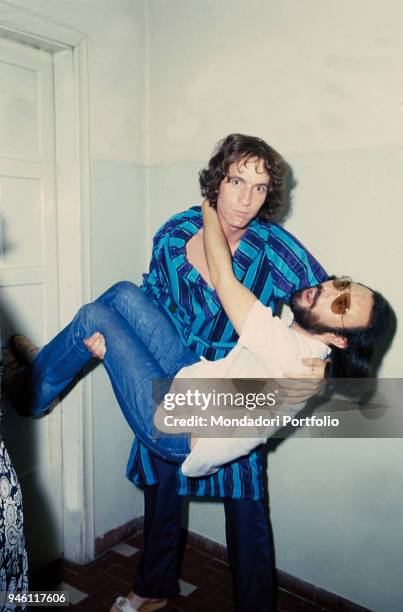 Italian singer-songwriter Rino Gaetano holding Italian singer Antonello Venditti in his arms behind the scenes of Vota la voce. Bologna , 1978