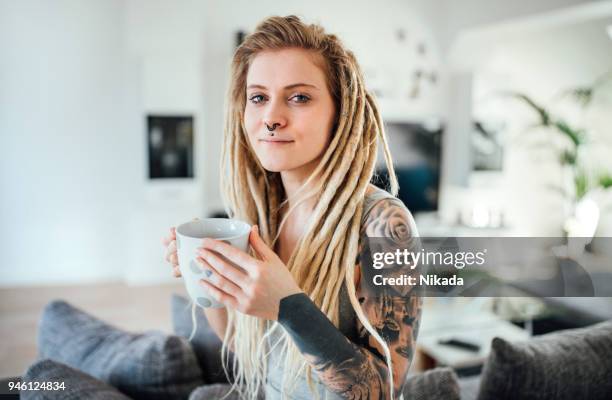 porträt des jungen tätowierte frau entspannt zu hause - coiffure punk stock-fotos und bilder