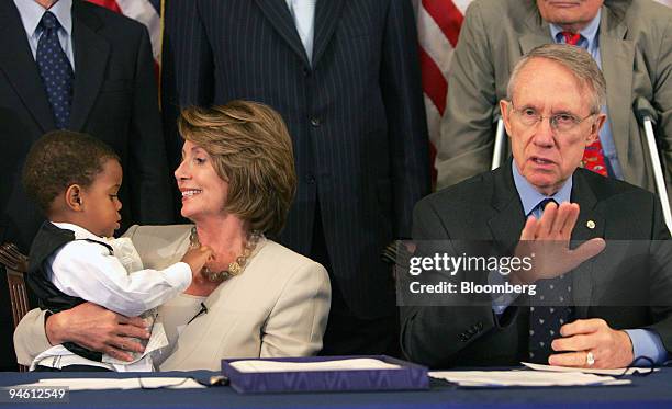 Nancy Pelosi, left, speaker of the U.S. House of Representatives, lets Malik Bruce play with her necklace, while Harry Reid, the U.S. Senate majority...