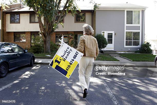Alison Lalla, a salesperson with 1st Choice Realty, carries a sign to place in the yard of a townhouse she's listing for sale in Crofton, Maryland...