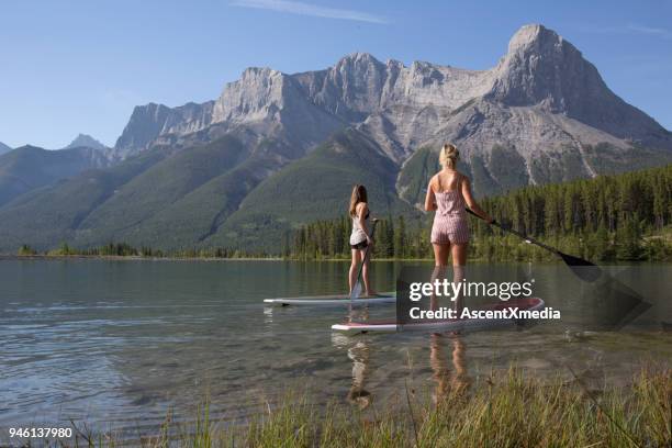 tablero de paleta dos jóvenes en lago de montaña - bow valley fotografías e imágenes de stock