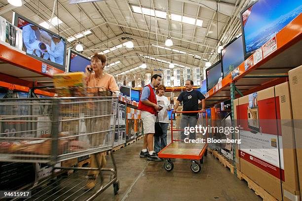 Costco store employe Luis Leon, center, explains the differences in flat screen televisions to customers Marie Currie and Robert Truitt as they shop...