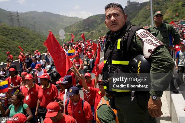 Military troops patrol as people march during the inauguration of a vital bridge that connects Caracas to La Guaira, Venezuela, on Thursday June 21,...
