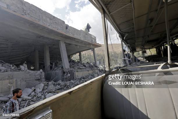 Journalist inspects the wreckage of a building described as part of the Scientific Studies and Research Centre compound in the Barzeh district, north...