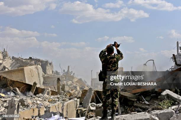 Syrian soldier inspects the wreckage of a building described as part of the Scientific Studies and Research Centre compound in the Barzeh district,...