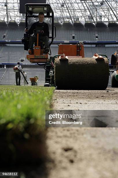 Workers lay new turf in the Munich Allianz Arena in Munich, Germany, on Wednesday, May 17, 2006. Workers laid new grass before the start of the 2006...