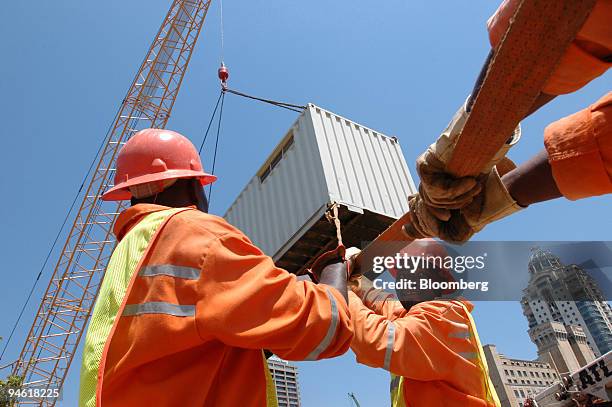 Workers help shift a container, elevated by a crane, into positon during the construction of the Gautrain underground railway, in Sandton,...