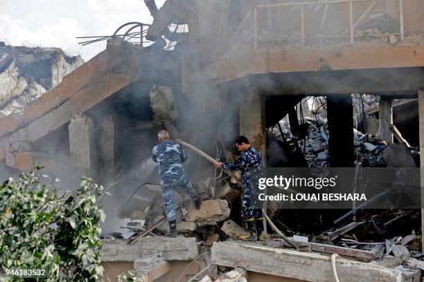 Syrian soldiers extinguish a fire in the wreckage of a building described as part of the Scientific Studies and Research Centre compound in the...