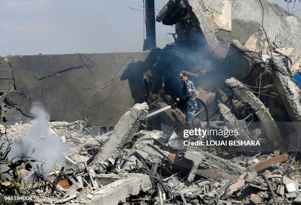 Syrian soldier sprays water on the wreckage of a building described as part of the Scientific Studies and Research Centre compound in the Barzeh...