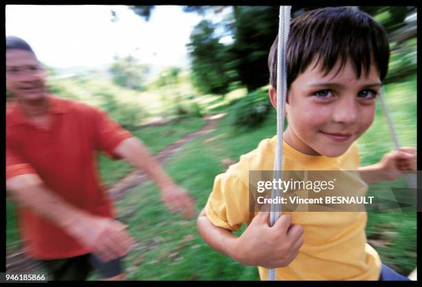 PETIT GARCON SUR UNE BALANCOIRE.