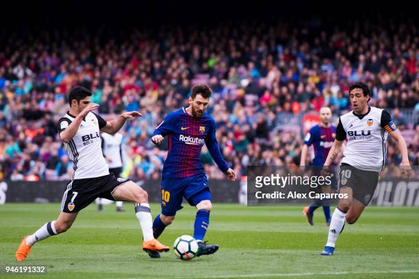 Lionel Messi of FC Barcelona conducts the ball between Goncalo Guedes and Daniel Parejo of Valencia CF during the La Liga match between Barcelona and...