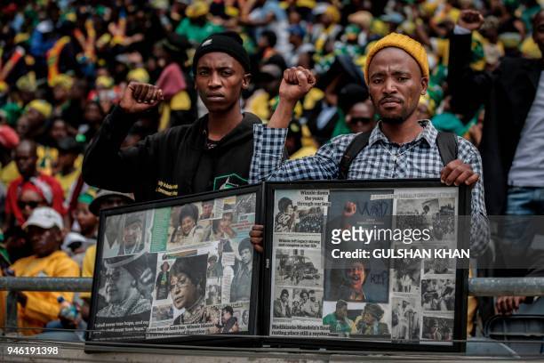Mourners with raised clinched fists stand watching from the stands of the full 37,500-seater Orlando Stadium, in the township of Soweto, the funeral...