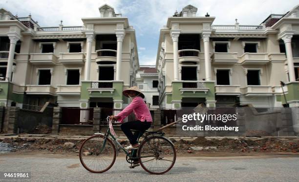 Women rides her bike past residential apartments under construction in a suburb of Hanoi, Vietnam on Sunday, August 20, 2006.