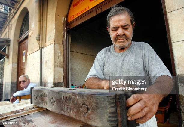 Giacomo Ingrassia repairs restores the wooden hanging fixture of an antique lamp at his family's antique furniture restoration shop in Palermo,...