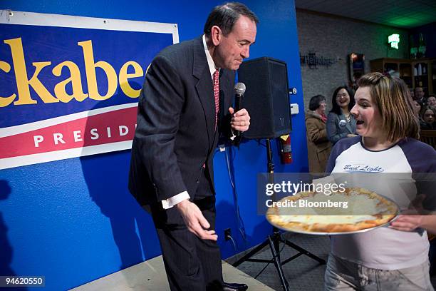 Mike Huckabee, former governor of Arkansas and Republican presidential hopeful, jokes with to a waitress as he speaks during a campaign stop at...