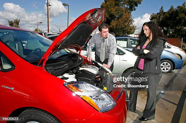 Salesman Shawn Hayes points out the features of a Toyota Prius Hybrid to prospective buyer Daniela Provenzano at the Toyota of El Cajon dealership in...