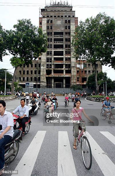 People ride past a commercial building site in Hanoi, Vietnam on Sunday, August 20, 2006.