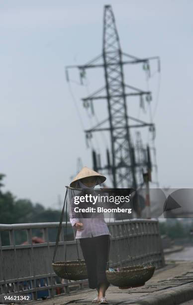 Woman walks along a highway near powerlines in Hanoi, Vietnam on Sunday, August 20, 2006.