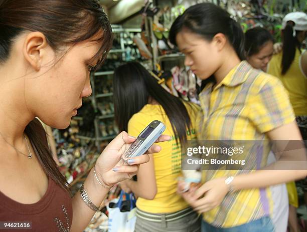Woman uses her mobilephone to send a text messages iin Hanoi, Vietnam on Saturday, August 19, 2006.