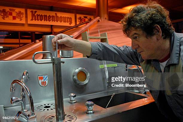 Worker checks a sample of beer during the fermentation process at the Kronenbourg beer brewery in Obernay, France, on Tuesday, December 2007....