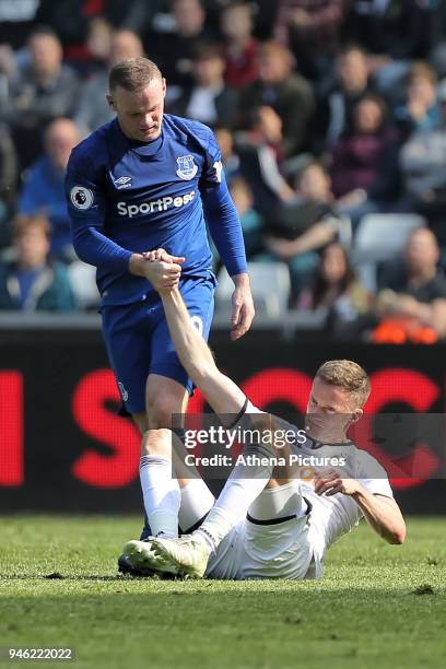 Wayne Rooney of Everton helps Andy King of Swansea City to get to his feet during the Premier League match between Swansea City and Everton at The...