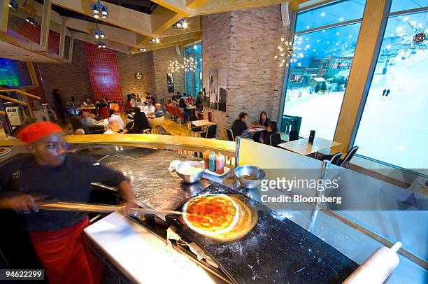 An employee prepares pizza at "Apres," a cocktail lounge bar and restaurant, at Ski Dubai at the Mall of the Emirates in Dubai, United Arab Emirates,...