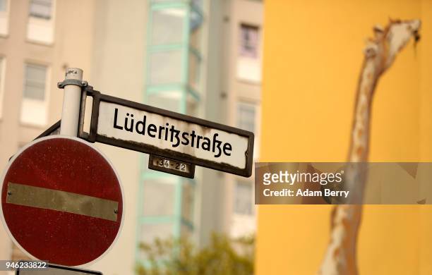 Street sign indicating a street named after the founder of German South West Africa, Adolf Luederitz, is seen in front of a mural of a giraffe on...