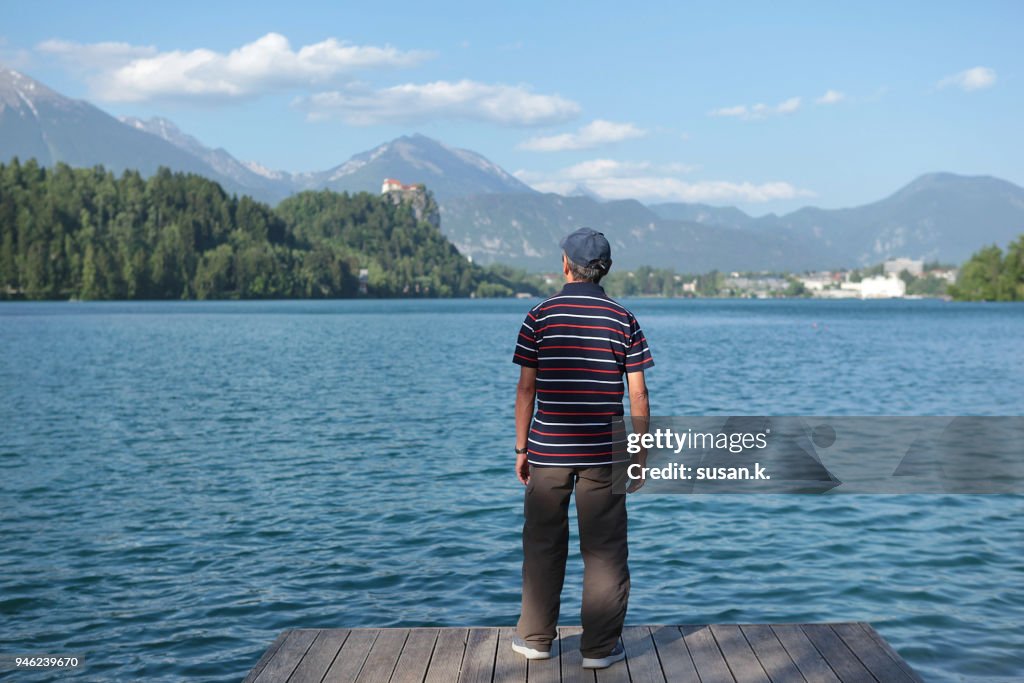 Portrait of a senior man admiring beautiful lake on sunny day.